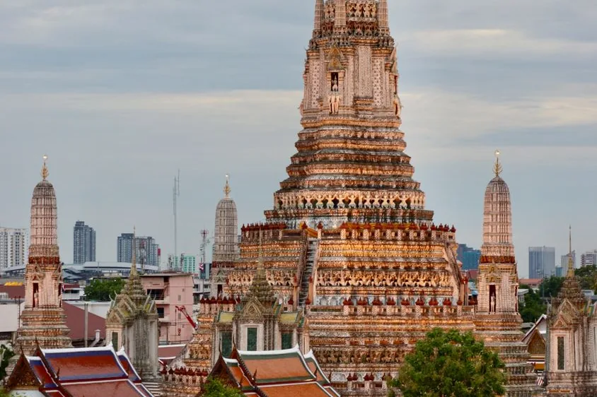 The central prang of Wat Arun and its smaller towers, with Bangkok buildings behind