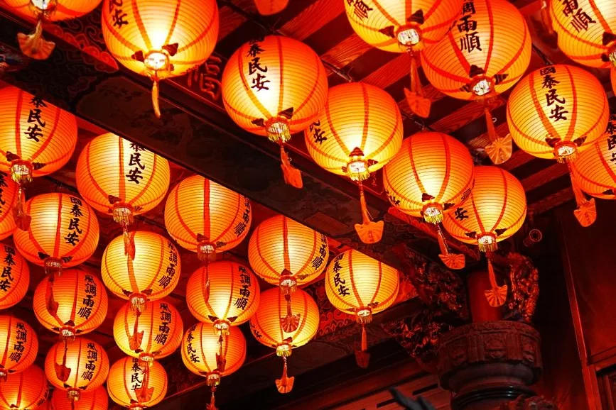 Rows of glowing red lanterns hung across the ceiling of a Chinese temple